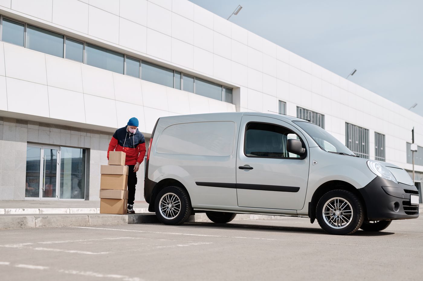 A driver unloading parcels from a van outside a building