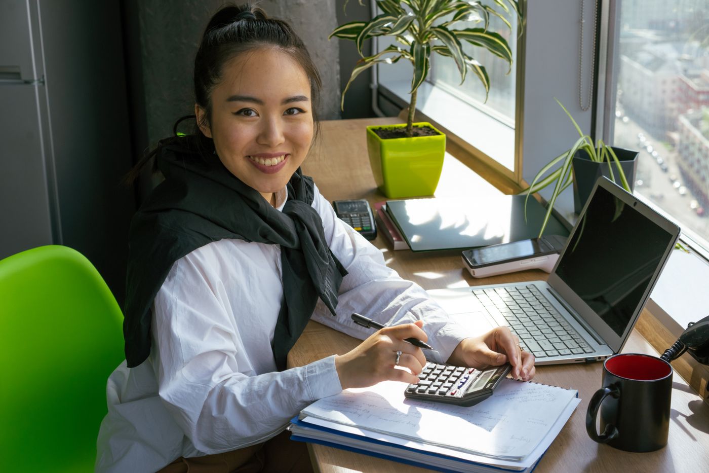 A finance officer working with a calculator and a laptop