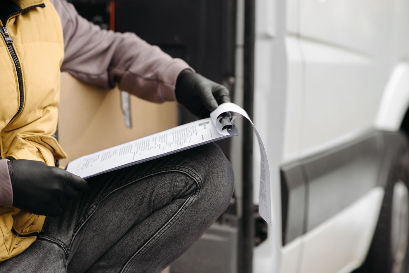 A driver checking a clipboard at the door of a van
