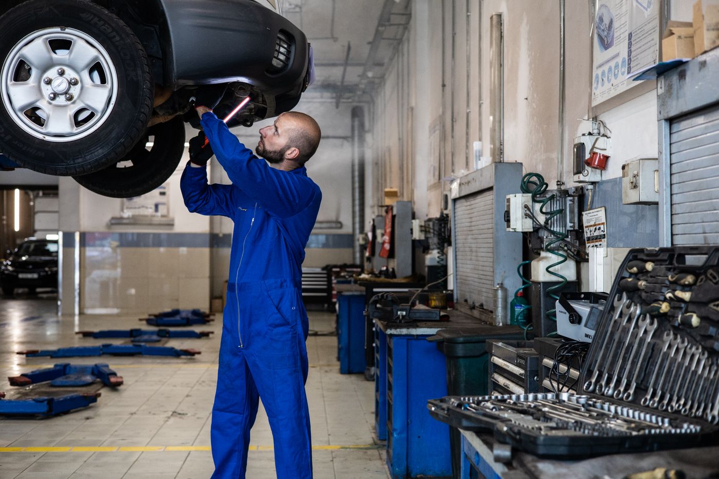 A mechanic working under a raised vehicle in a workshop