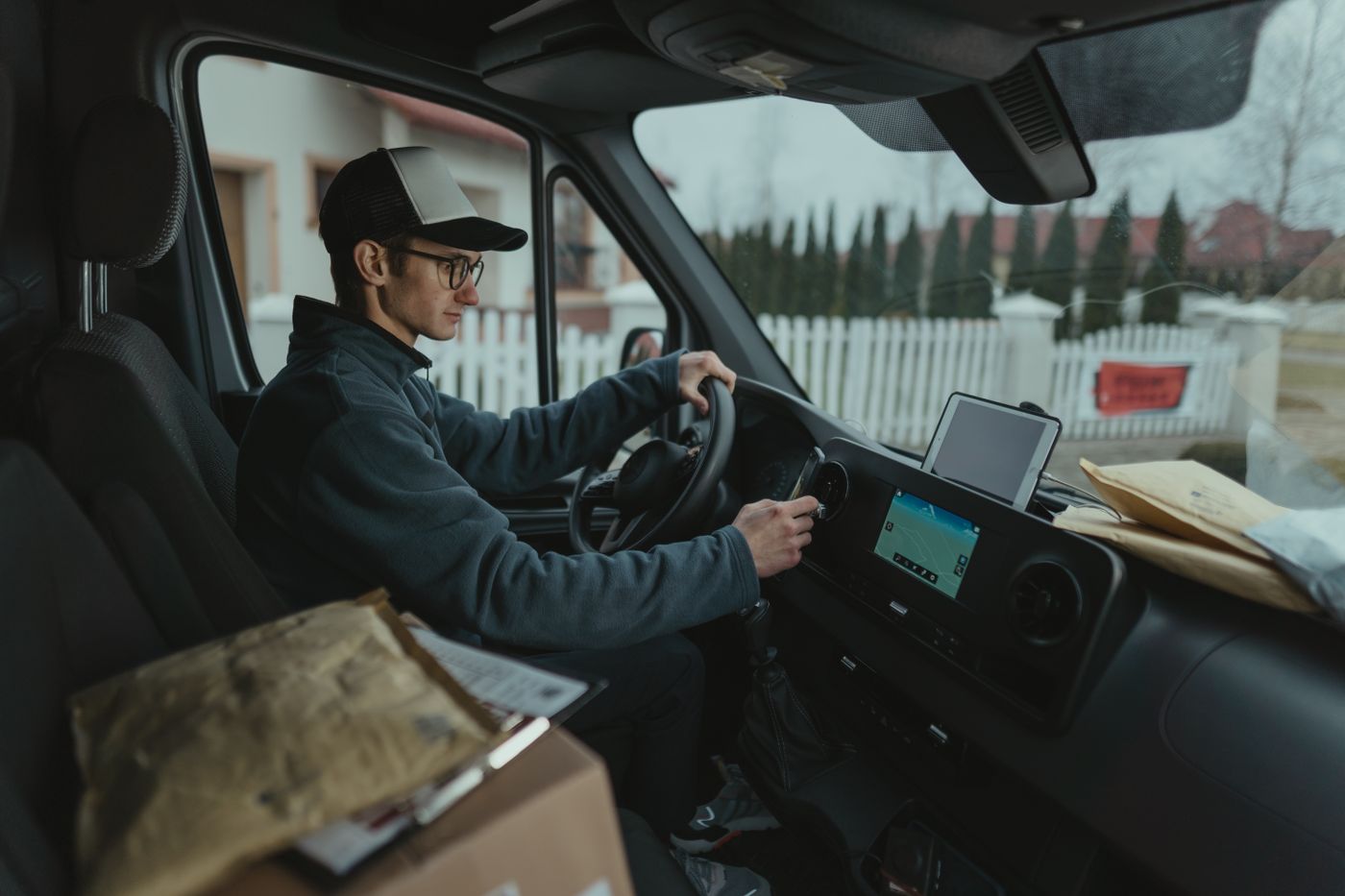 A driver at the wheel of a van, with a navigation screen on the dashboard